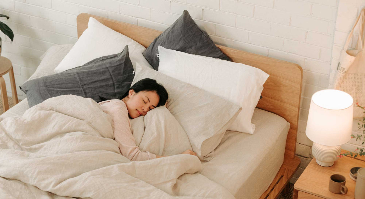 Woman looking cosy covered in hemp linen sheets and pillows